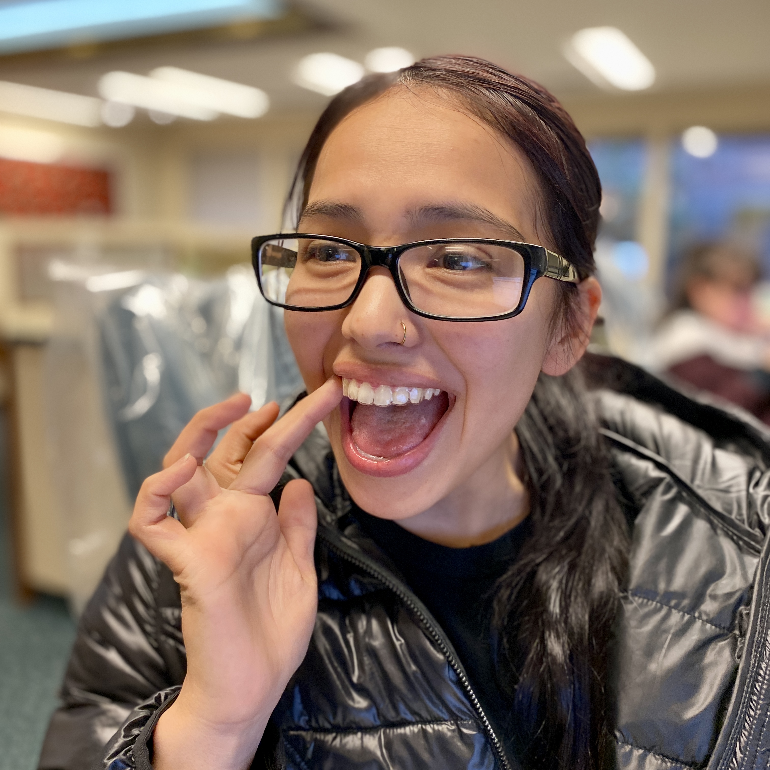 Smiling patient pointing to her teeth after clear aligner treatment at Rockwood Orthodontics